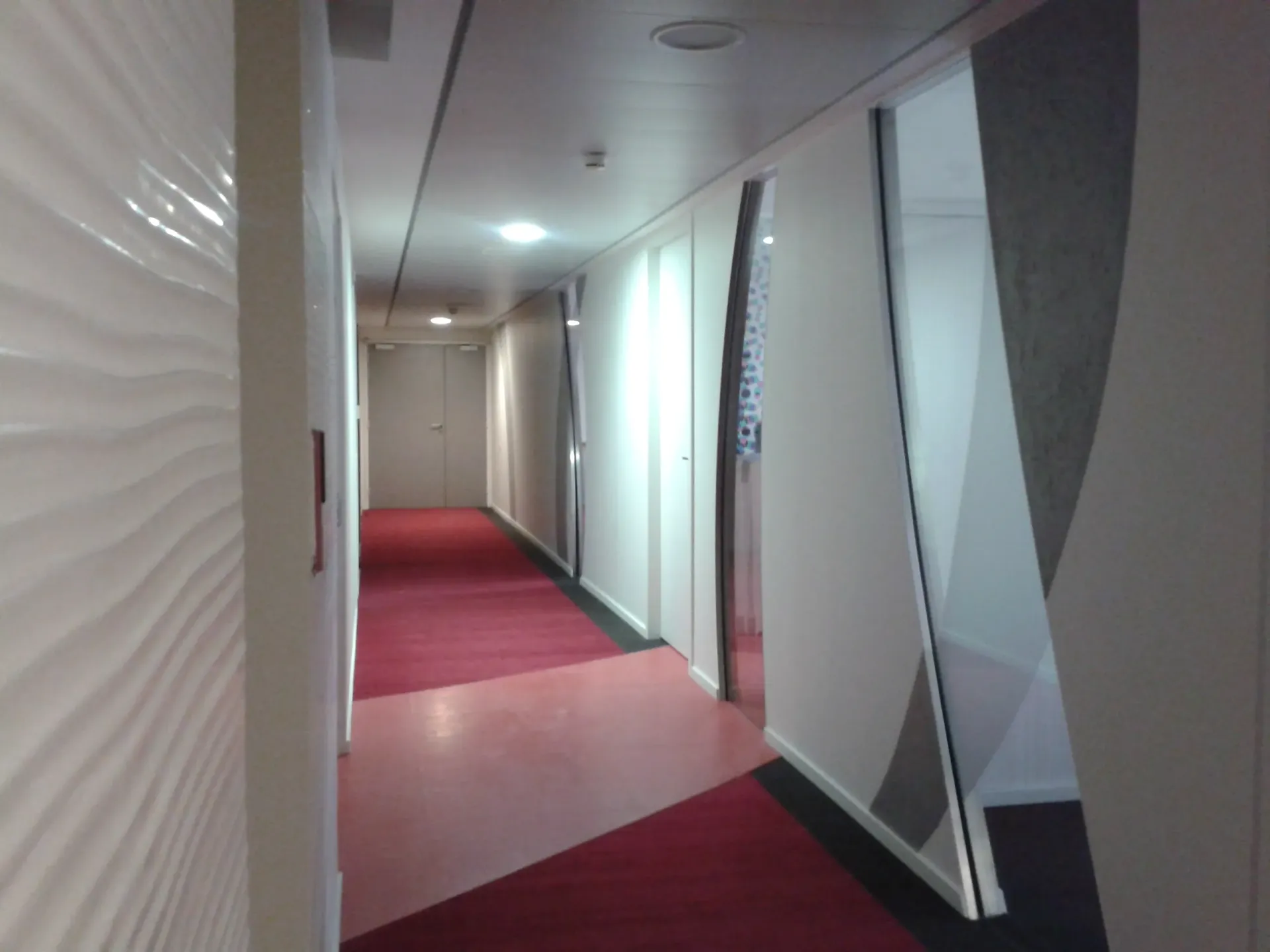 Un long couloir avec un tapis rouge et des murs blancs. Aménagement de bureaux et locaux professionnels - SPAC