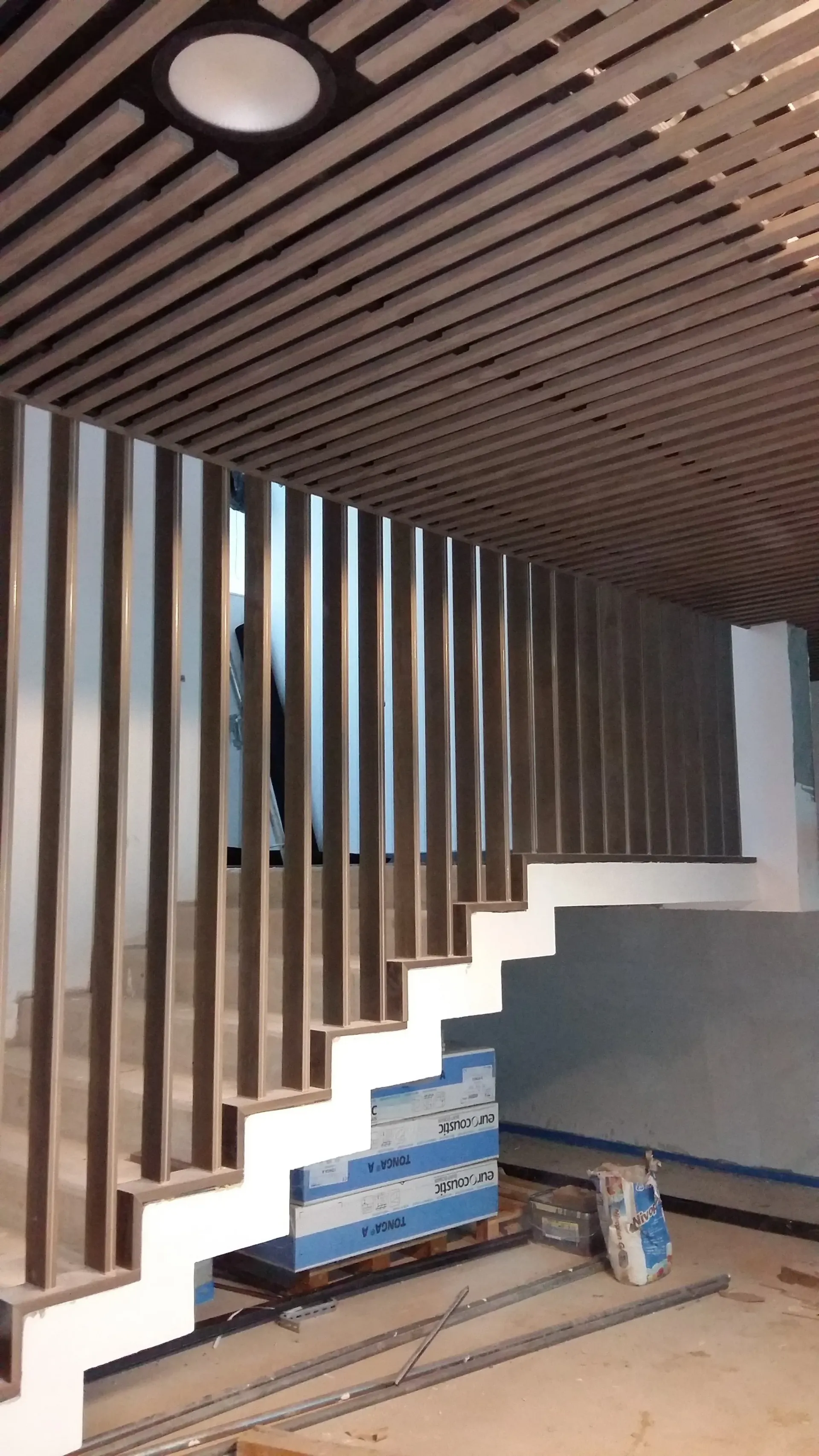 Un escalier est en cours de construction dans une pièce avec une rampe en bois. Aménagement SPAC