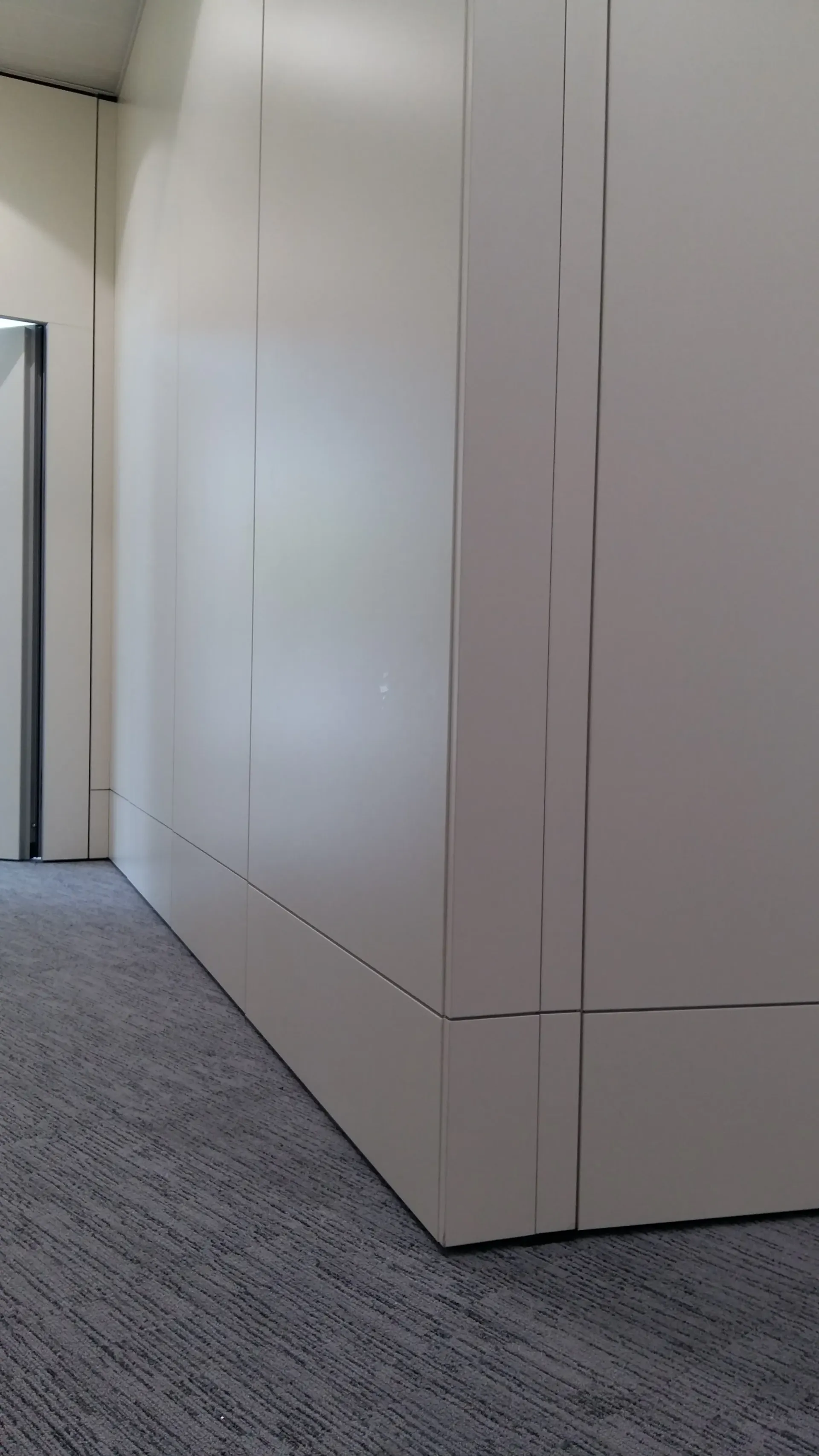 Un long couloir avec un tapis gris et des murs blancs. Aménagement de bureaux et locaux professionnels - SPAC