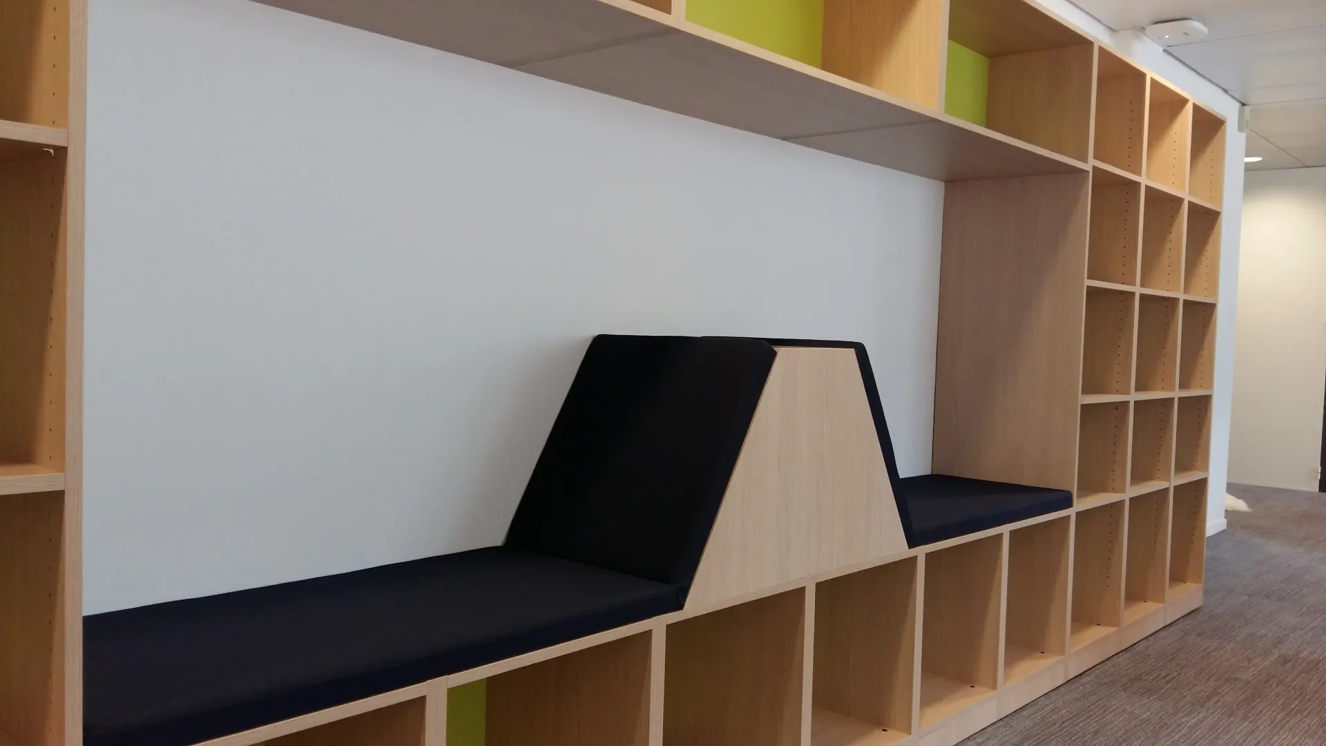 Une rangée d'étagères en bois avec un banc au milieu. Aménagement de bureaux et locaux professionnels - SPAC
