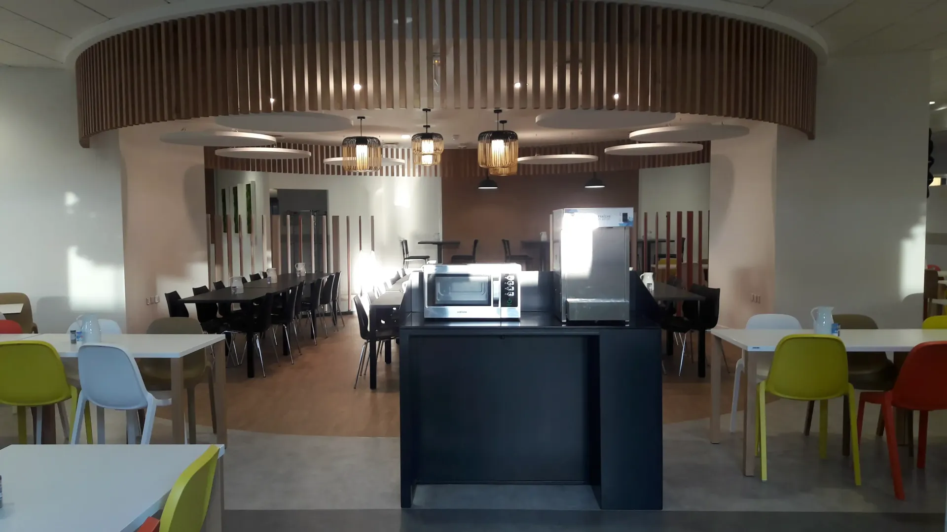 Une salle à manger avec tables et chaises et un micro-onde. Aménagement de bureaux et locaux professionnels - SPAC