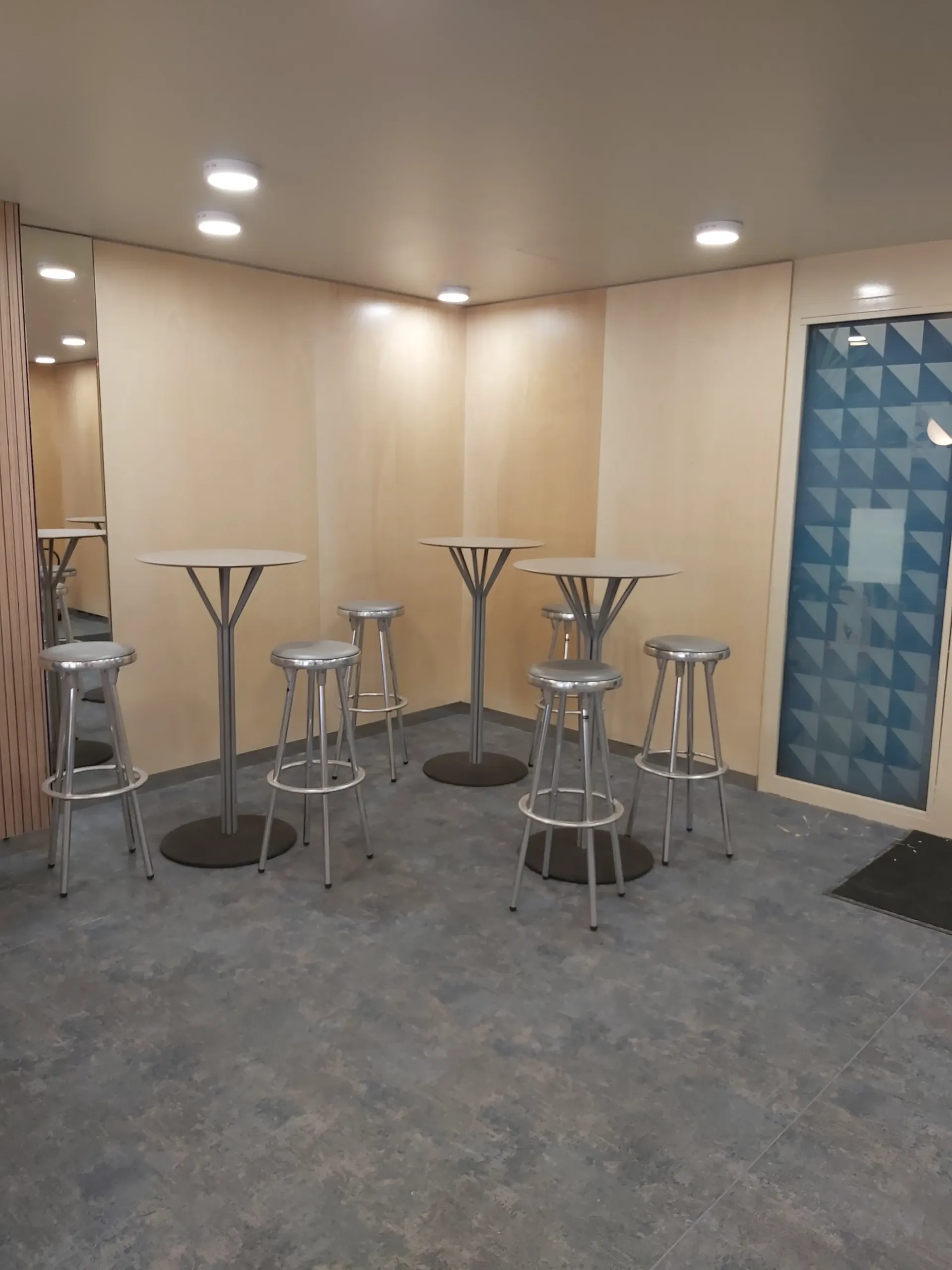 Une pièce avec des tables et des tabourets. Aménagement de bureaux et locaux professionnels - SPAC