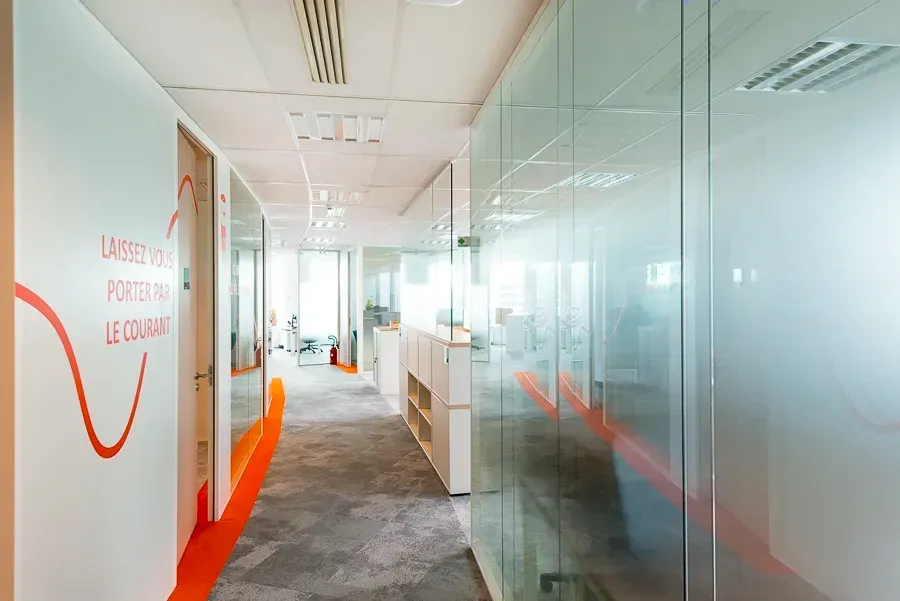 Un long couloir dans un immeuble de bureaux avec des murs en verre.  Aménagement de bureaux et locaux professionnels - SPAC