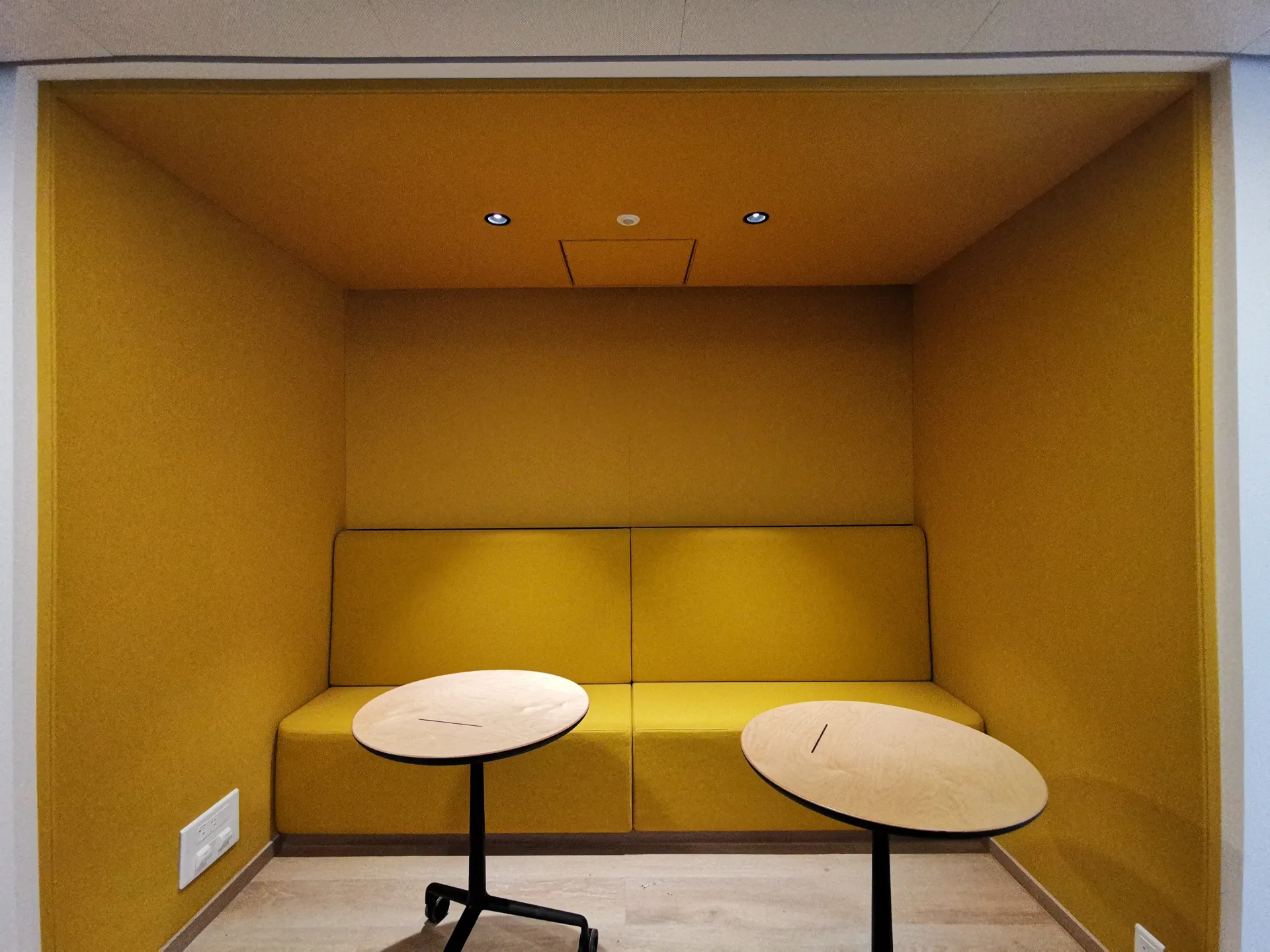 Une pièce avec un canapé jaune et deux tables. Aménagement de bureaux et locaux professionnels - SPAC