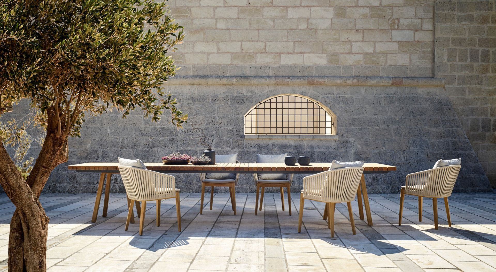 Een terras met een tafel en stoelen voor een bakstenen muur.