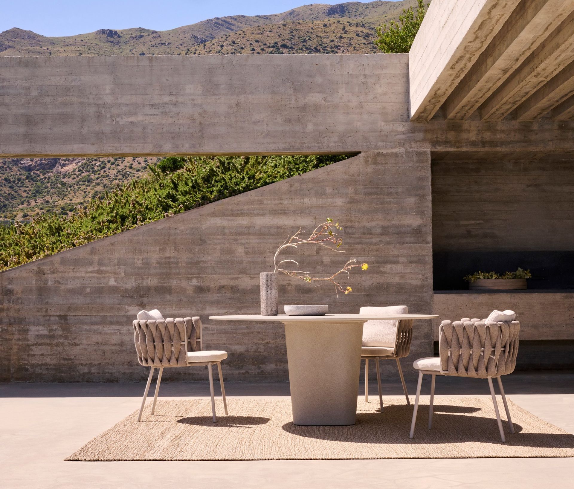 Een terras met een tafel en stoelen met bergen op de achtergrond