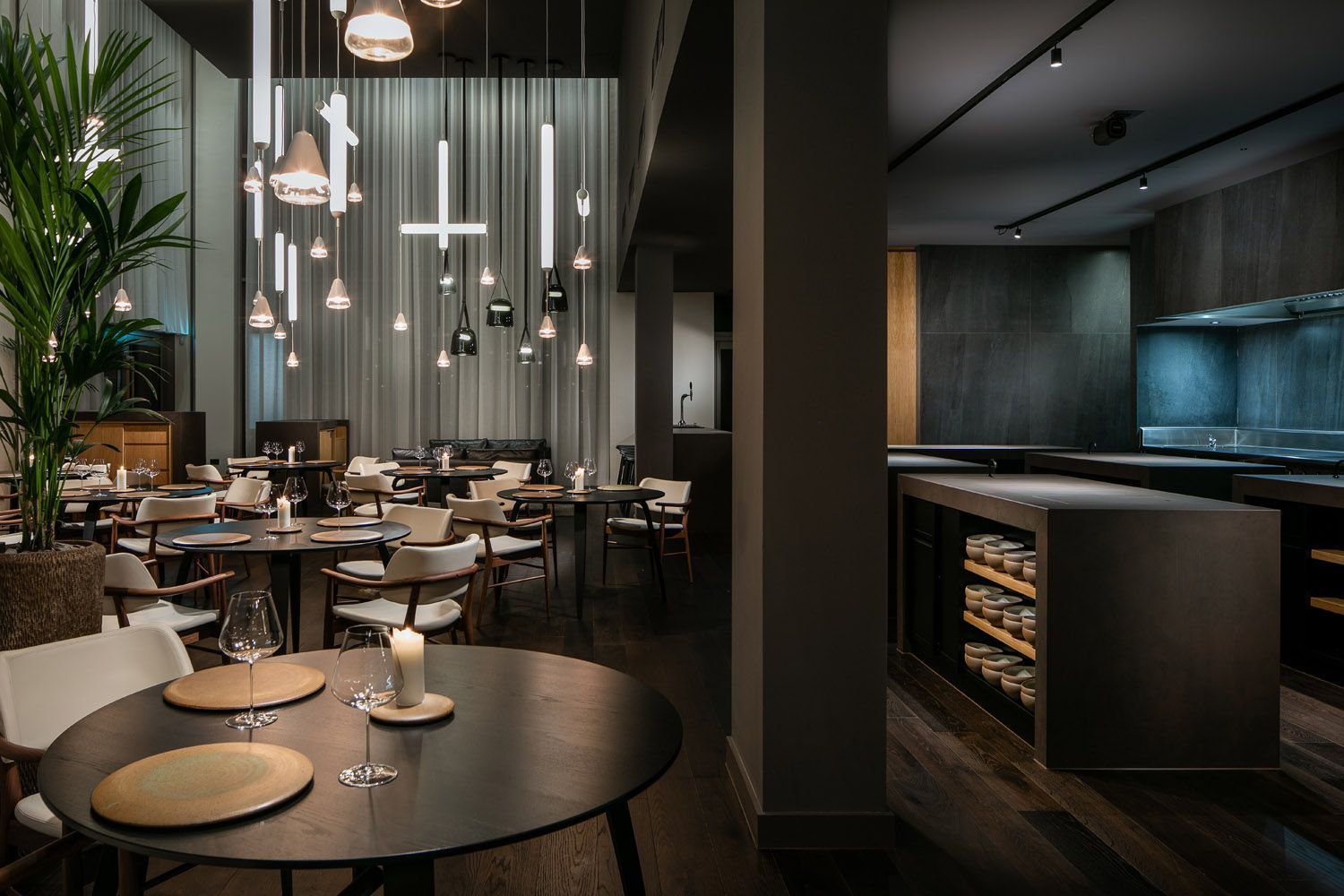 Een restaurant met veel tafels en stoelen en een kaars op tafel.