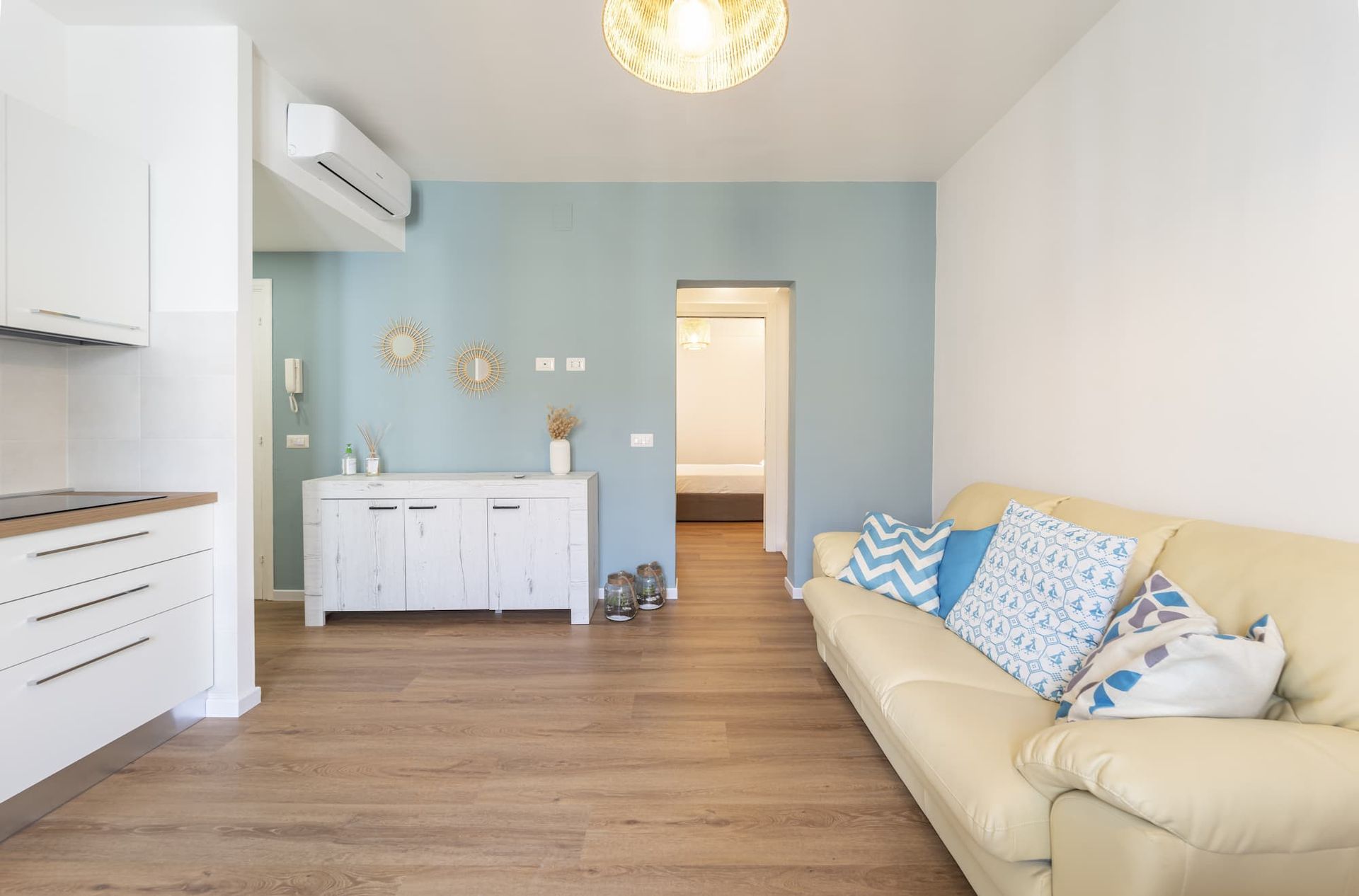 Een woonkamer met een gele bank en blauw-witte kussens.