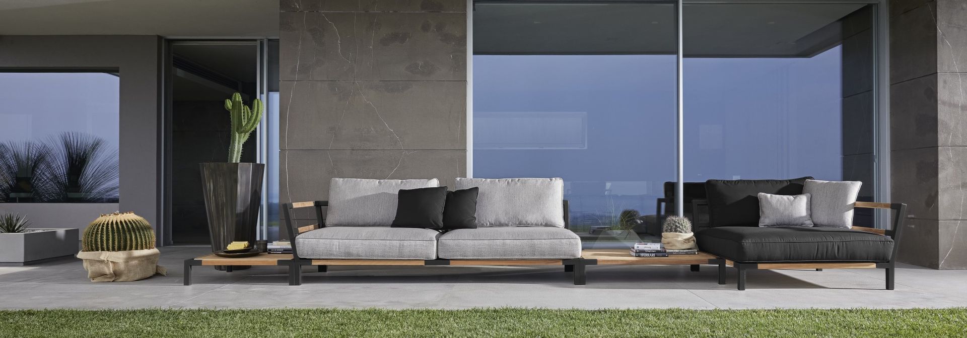 Een terras met een bank en stoelen voor een groot raam.