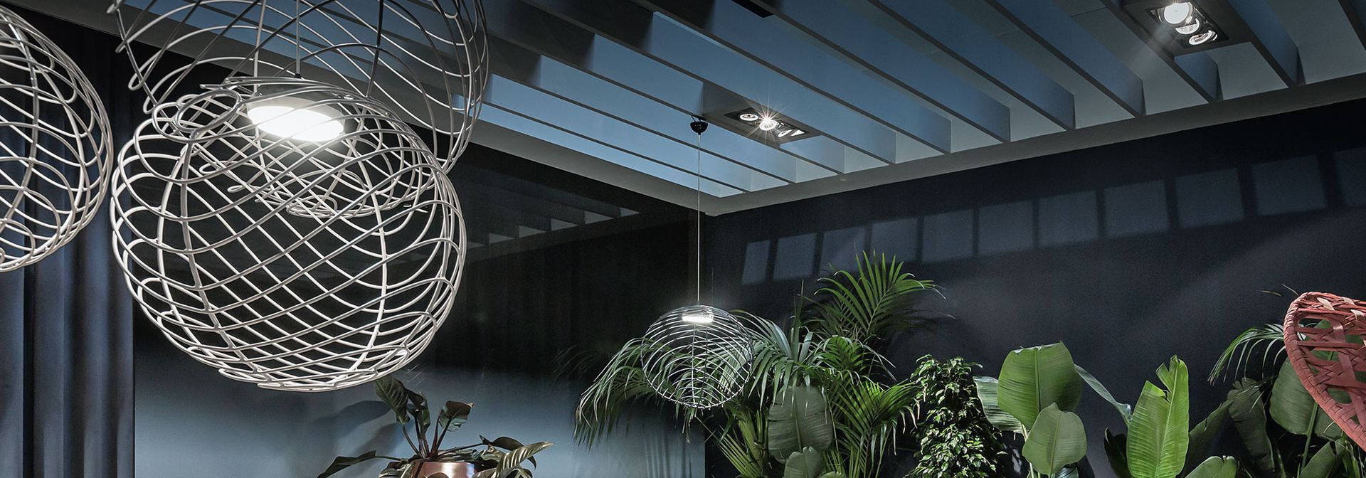Een kamer met veel planten en lampen die aan het plafond hangen