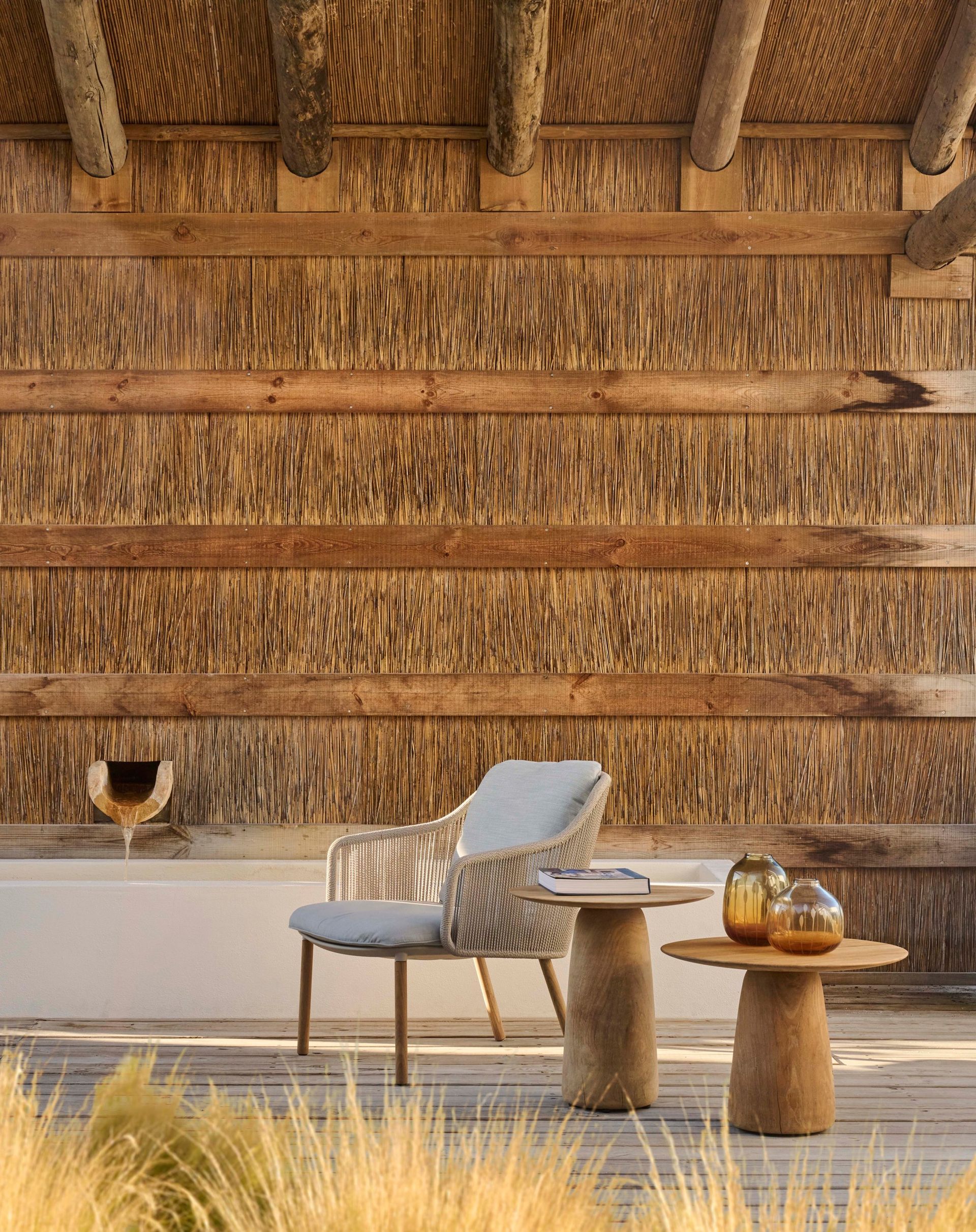 Een houten muur met daarvoor een stoel en twee tafels.