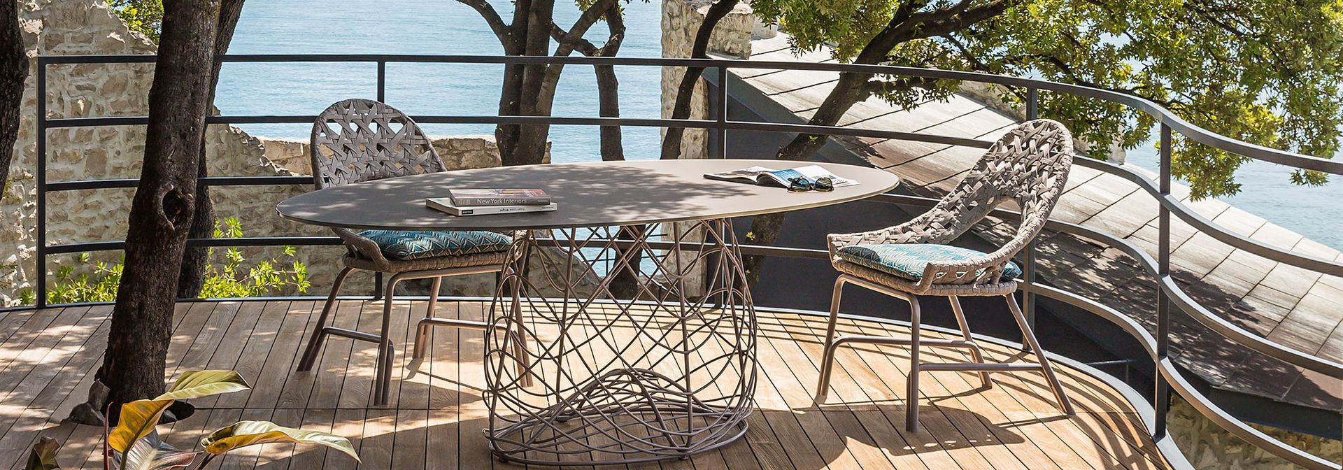 Een tafel en stoelen op een houten terras met uitzicht op het water.
