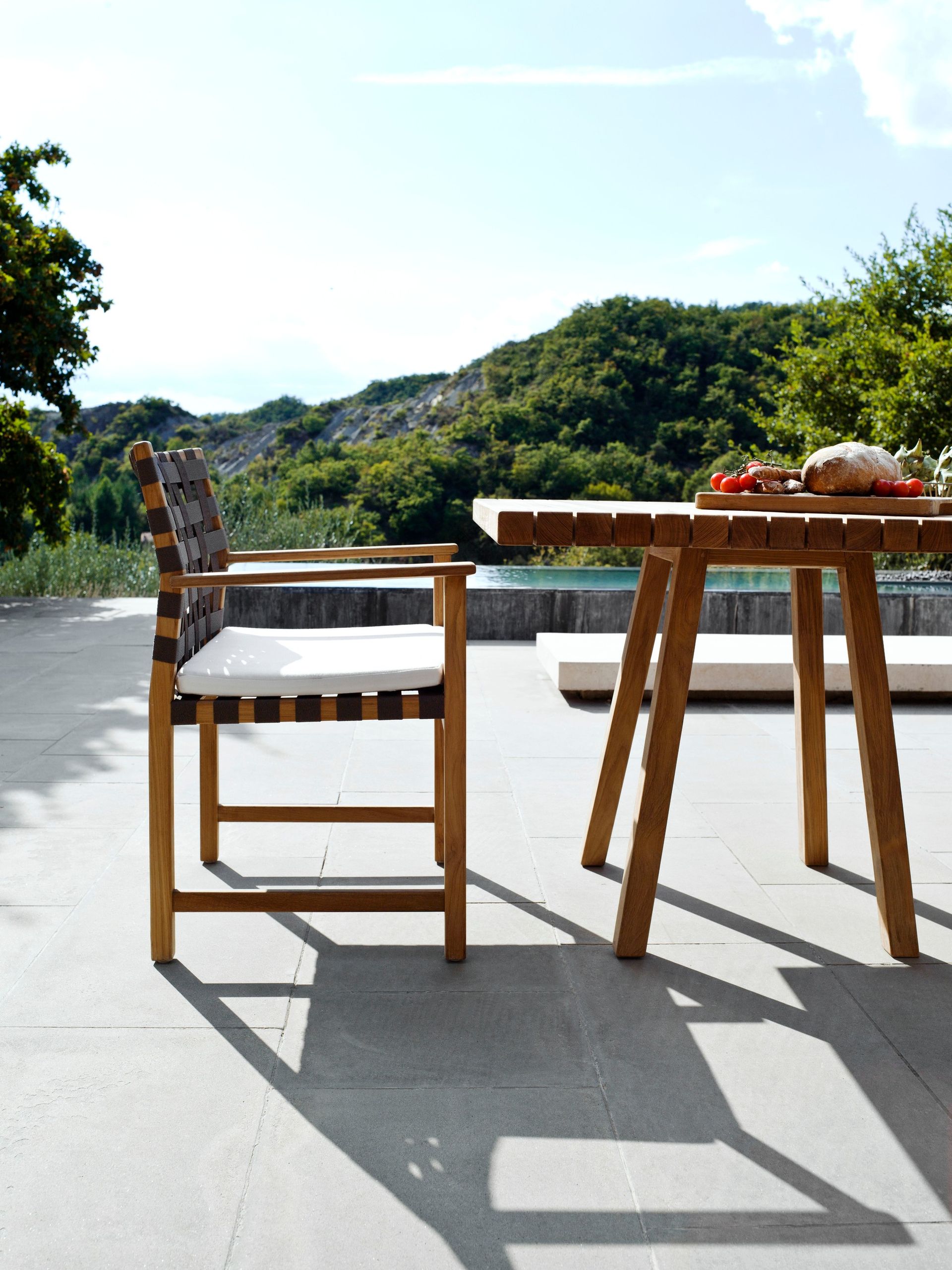 Een tafel en stoelen op een terras met bergen op de achtergrond