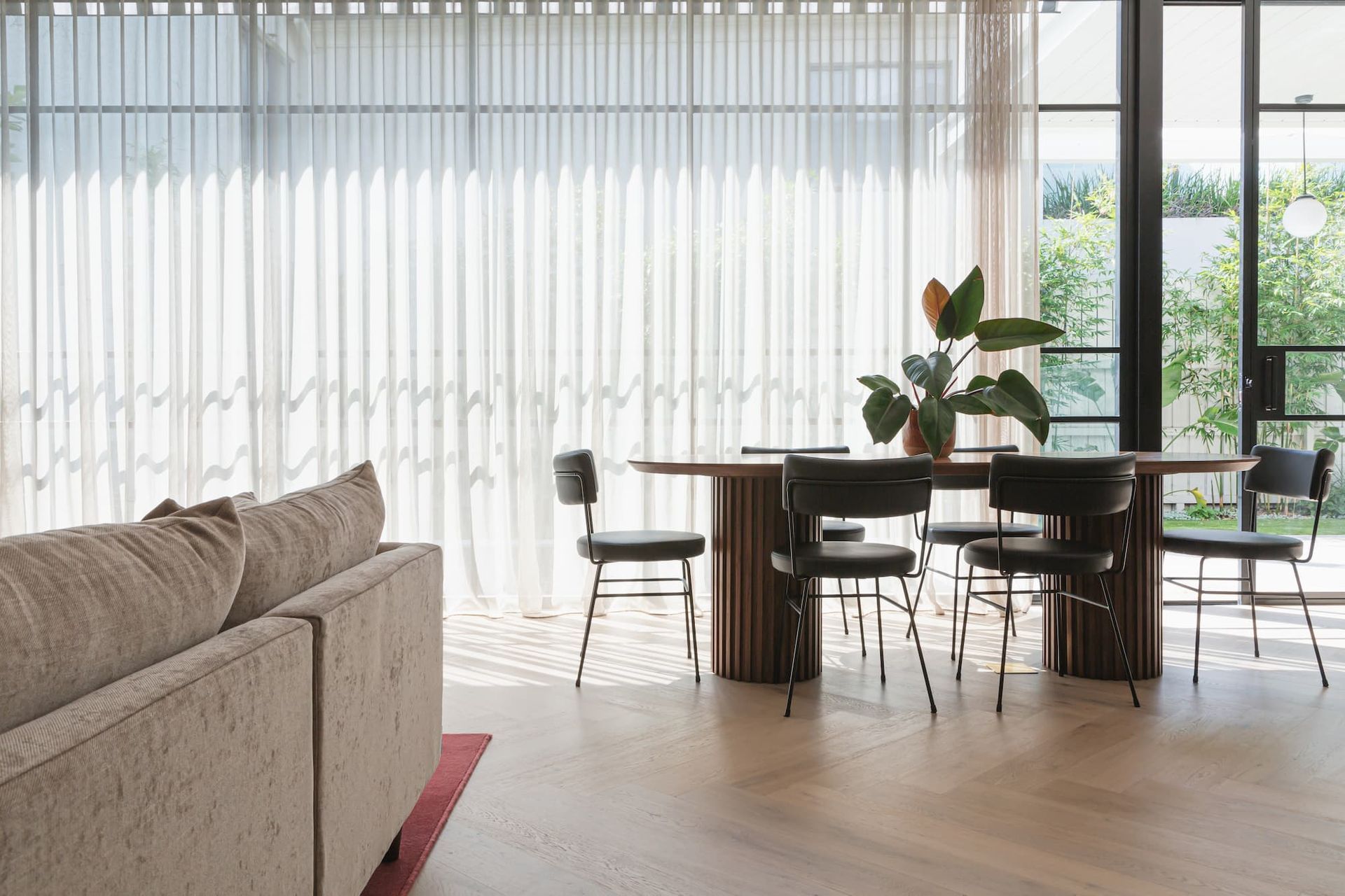 Een woonkamer met een eettafel, stoelen en een bank.