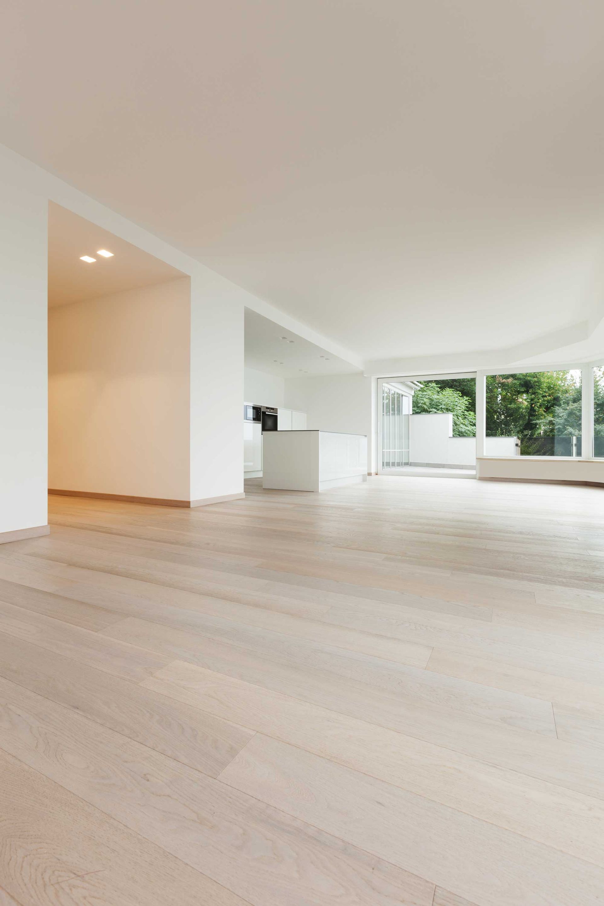Een lege woonkamer met hardhouten vloeren en witte muren.