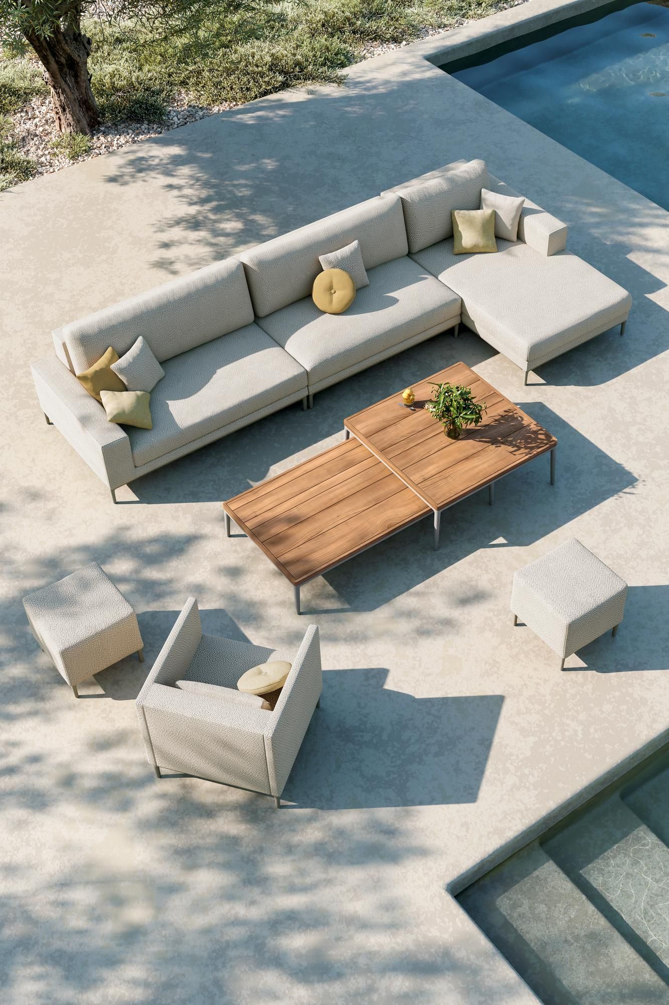 Een terras met een bank, stoelen en een salontafel naast een zwembad.
