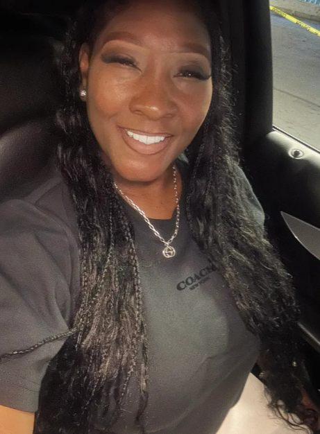 A woman wearing a coach shirt is smiling in a car