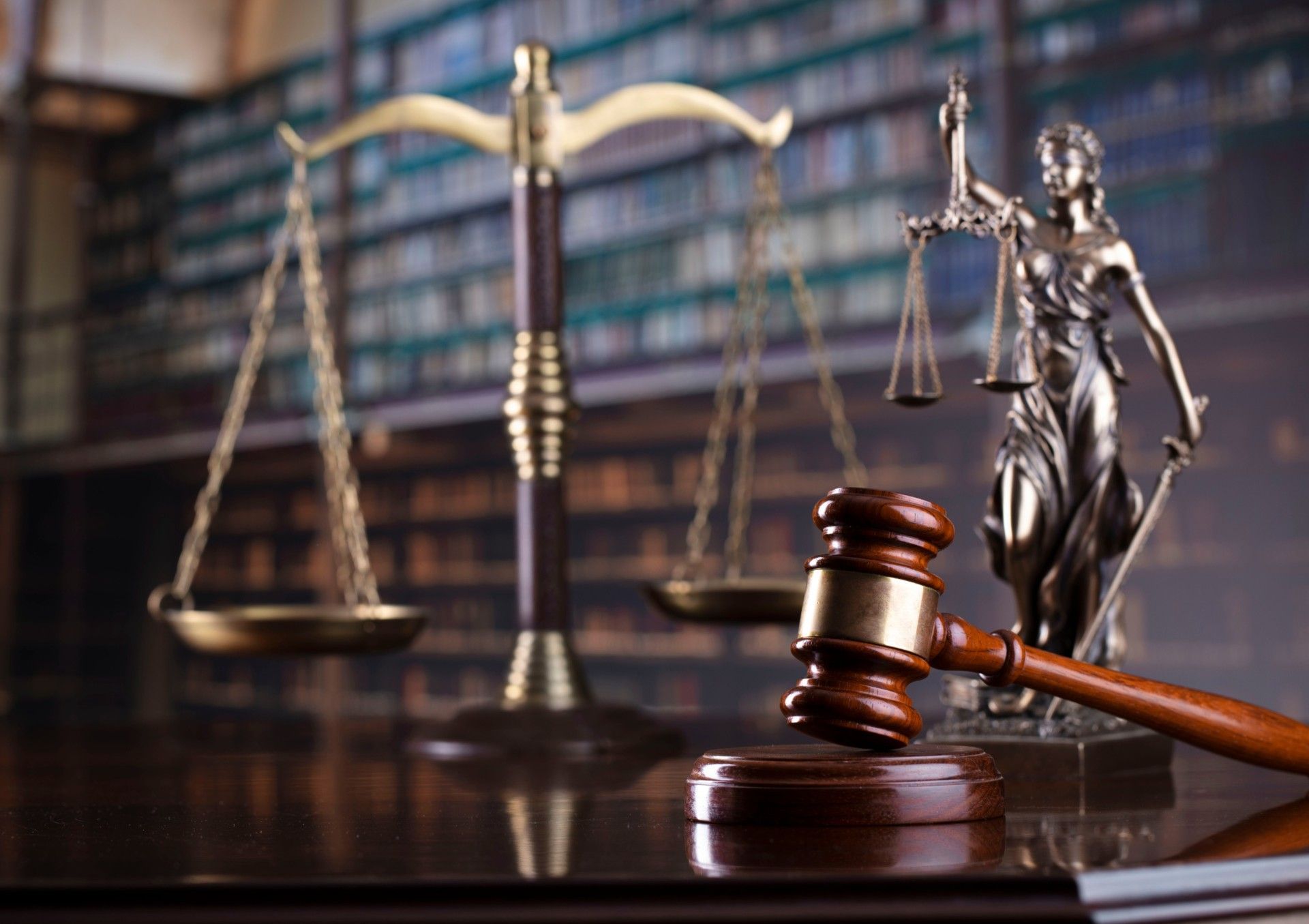 A statue of justice is sitting next to a wooden gavel and scales of justice.