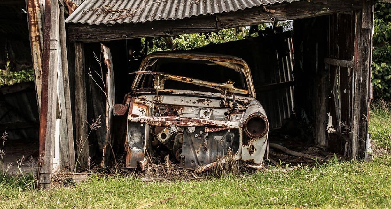 An Old Rusty Car is Parked in a Wooden Garage — Newport Recycling in Woree, QLD