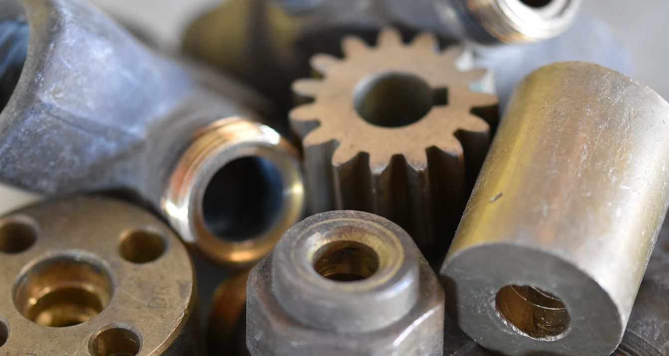 A Pile of Metal Parts Including Nuts and Gears Are Sitting on a Table — Newport Recycling in Woree, QLD