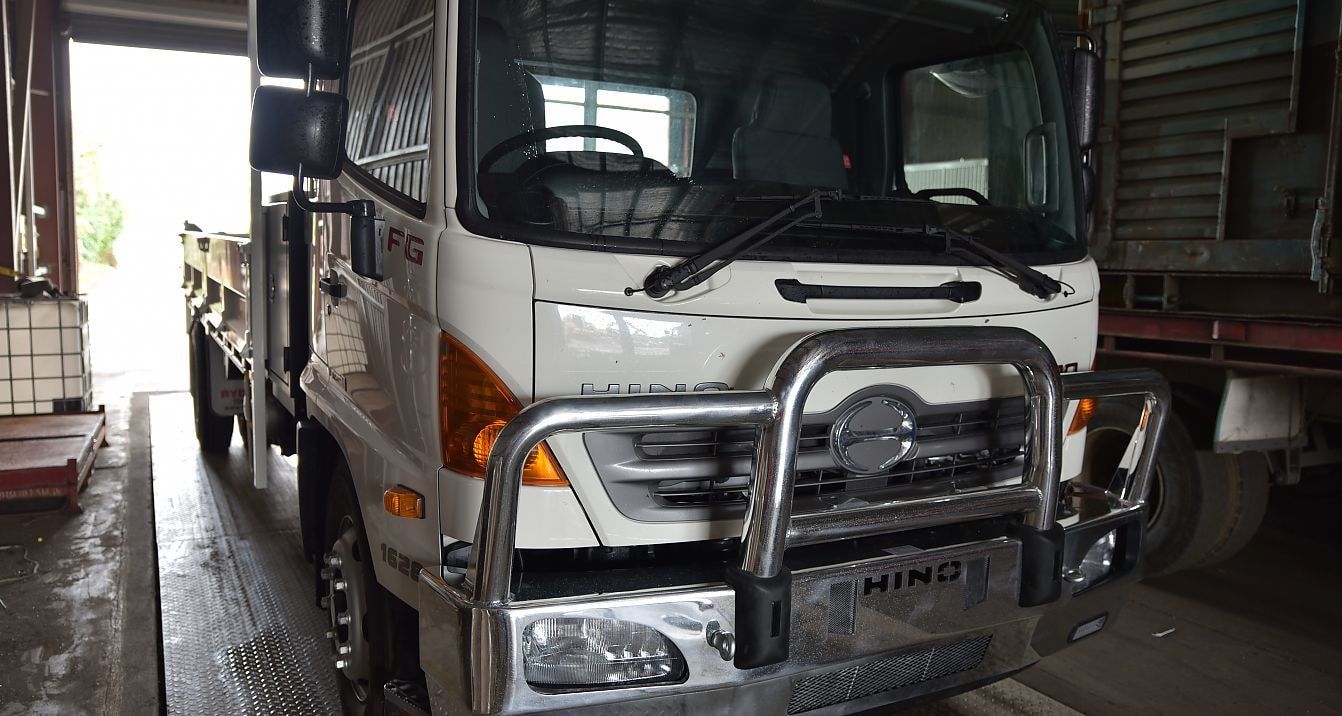 A White Truck With a Stainless Steel Bumper is Parked in a Garage — Newport Recycling in Woree, QLD