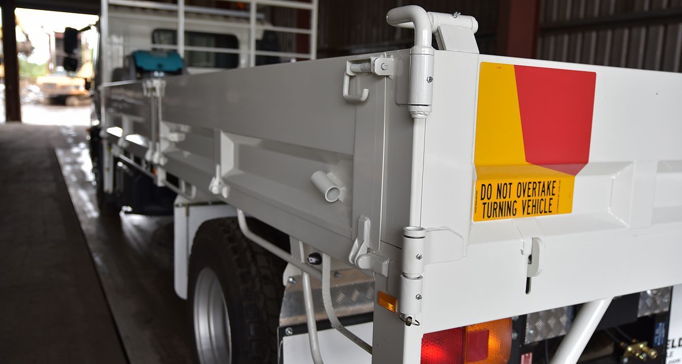 A White Truck With a Yellow and Red Sticker on the Back is Parked in a Garage — Newport Recycling in Woree, QLD