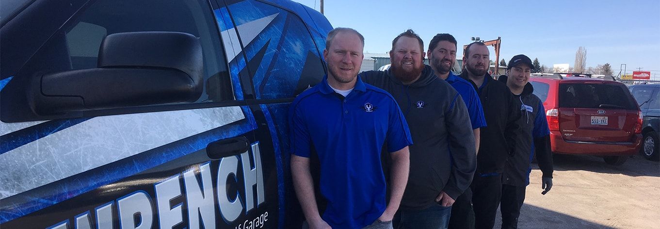 Group of people standing beside a blue branded vehicle outdoors on a sunny day. | Madison Automotive