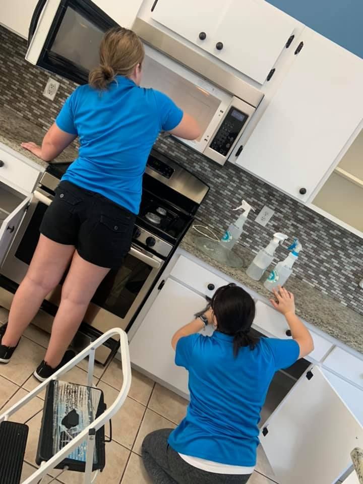 A stainless steel stove and dishwasher in a kitchen, with a protective white floor mat laid out in front of the stove.