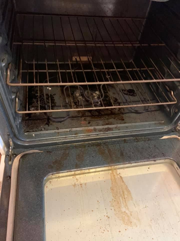 Dirty oven interior with burnt residue and greasy stains on the door and racks