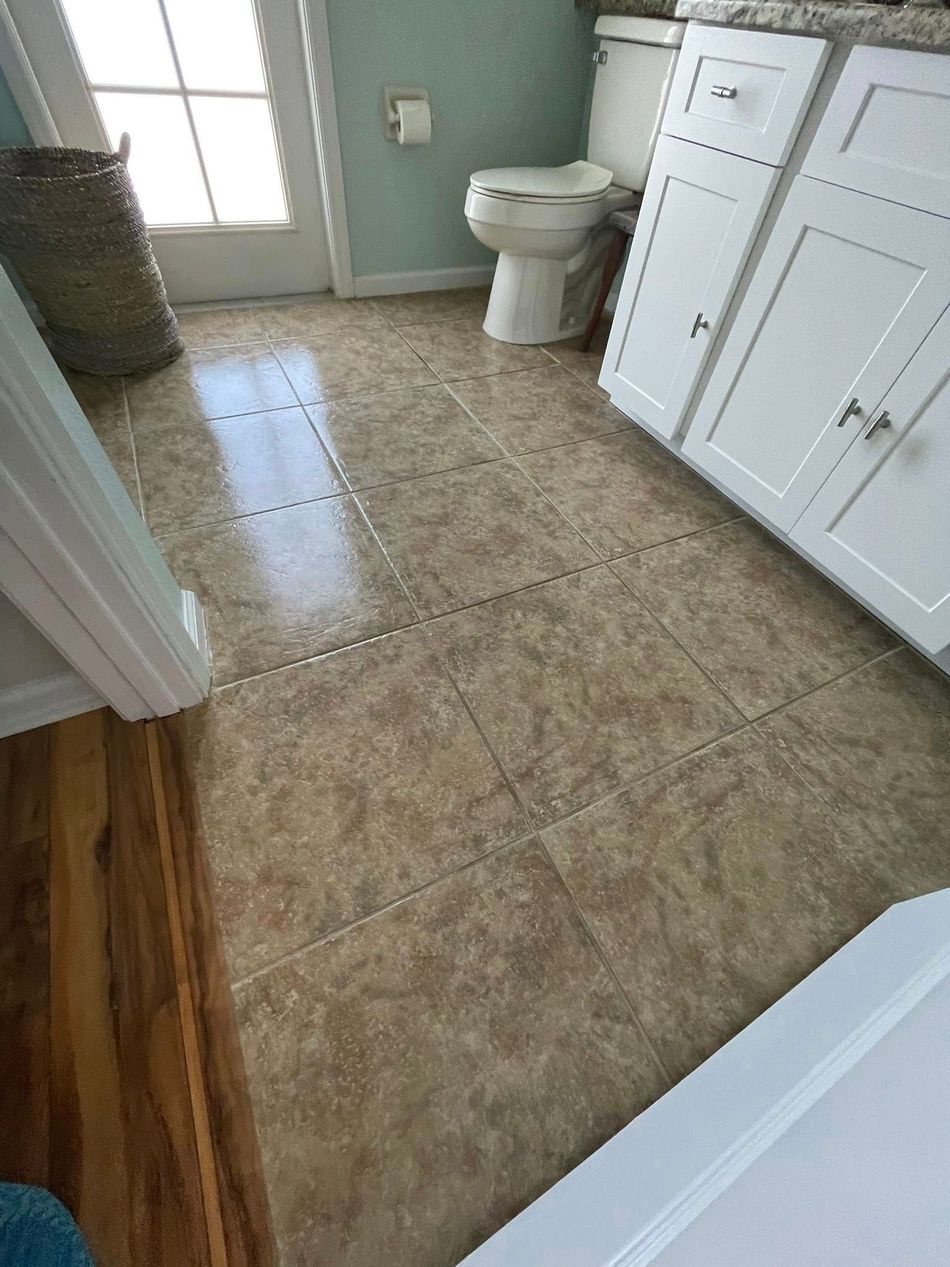 Bathroom with beige tile floor, toilet, white vanity, and a windowed door letting in light.