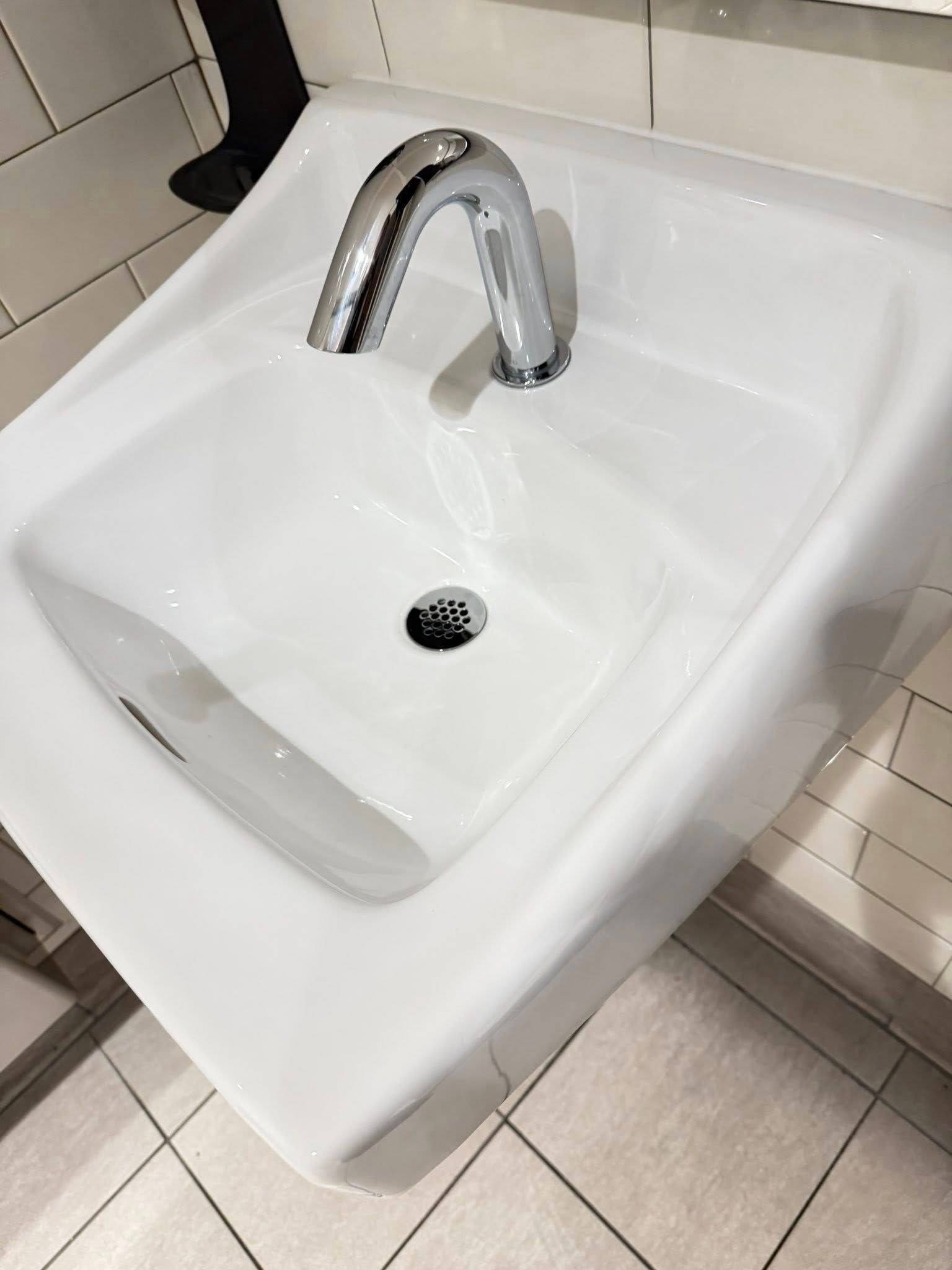 White ceramic wall-mounted sink with chrome faucet in a tiled restroom