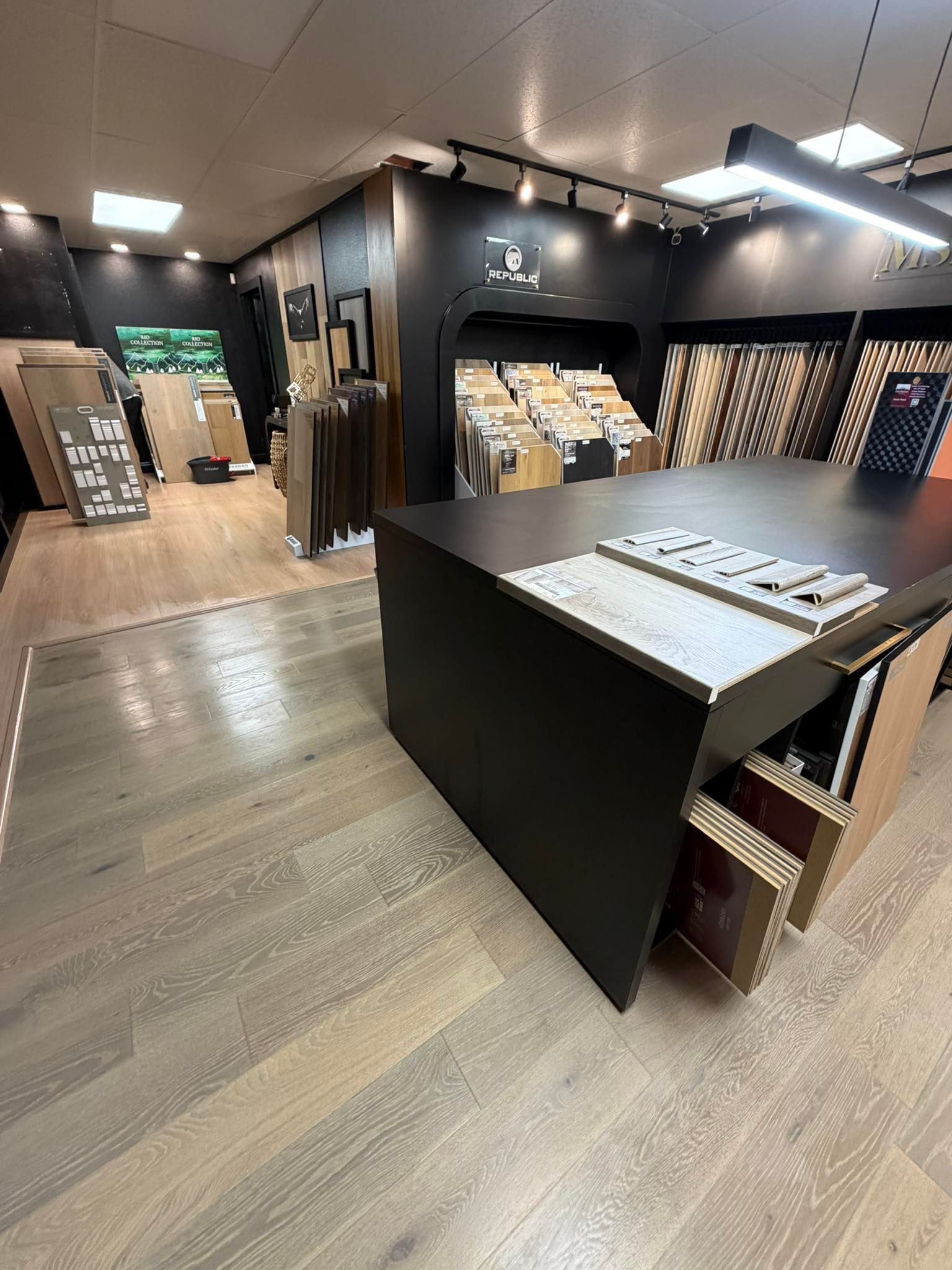 Modern retail store interior with clothing displays, black walls, and a central black counter