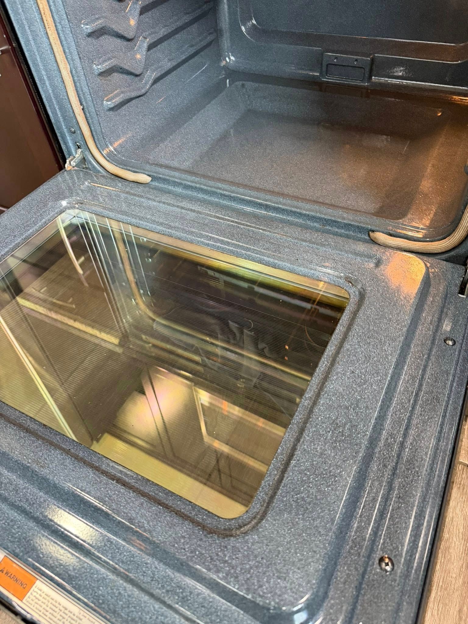 Open oven with glass window, showing the lit interior and baking rack.