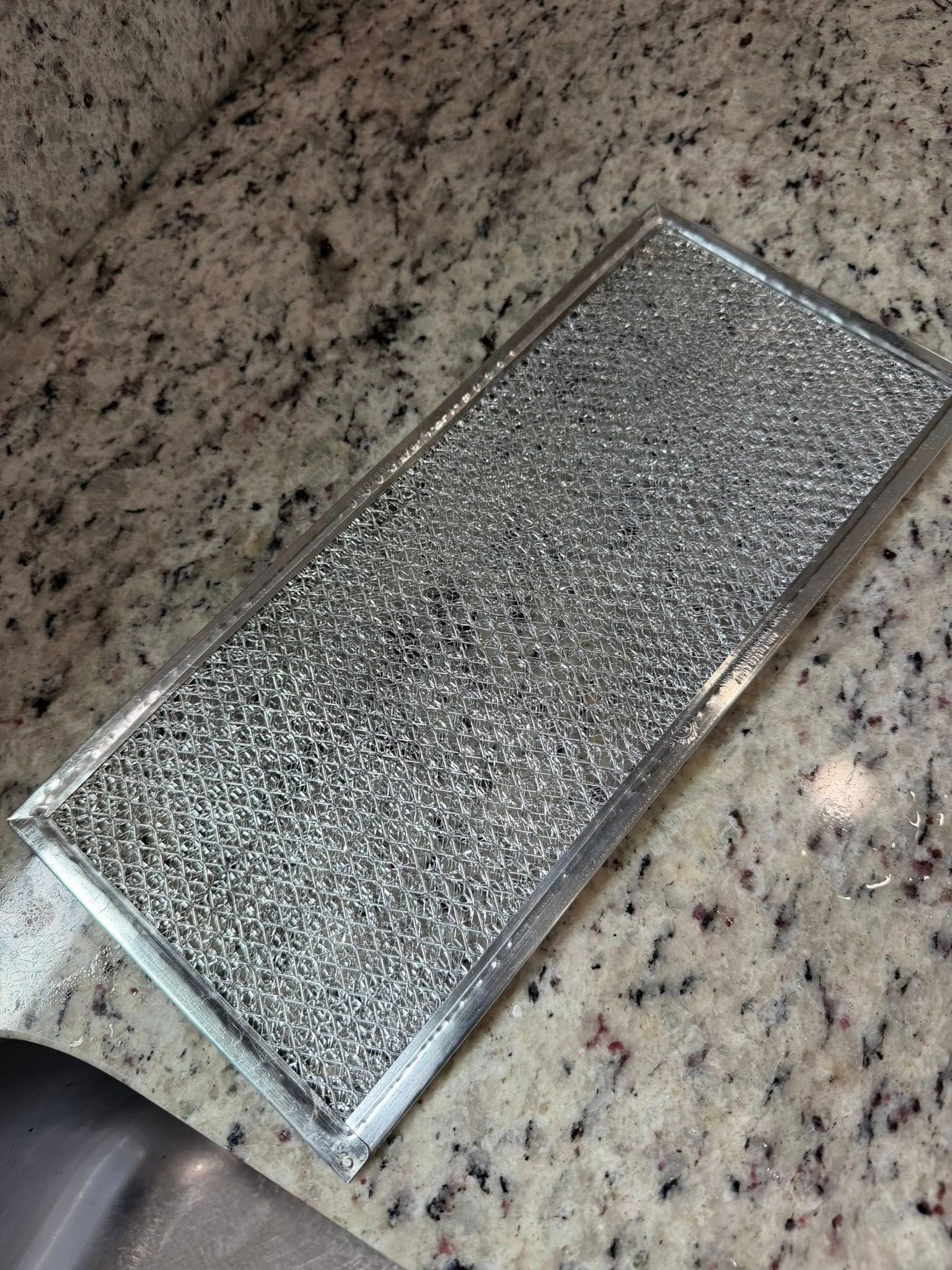 Textured silver rectangular metal filter on a speckled granite countertop.