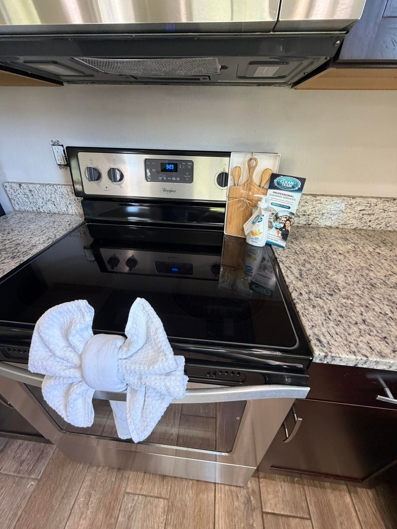 Kitchen stove with a white towel draped over the oven door and utensils on the stovetop.