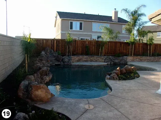 A large swimming pool with a wooden fence and a house in the background