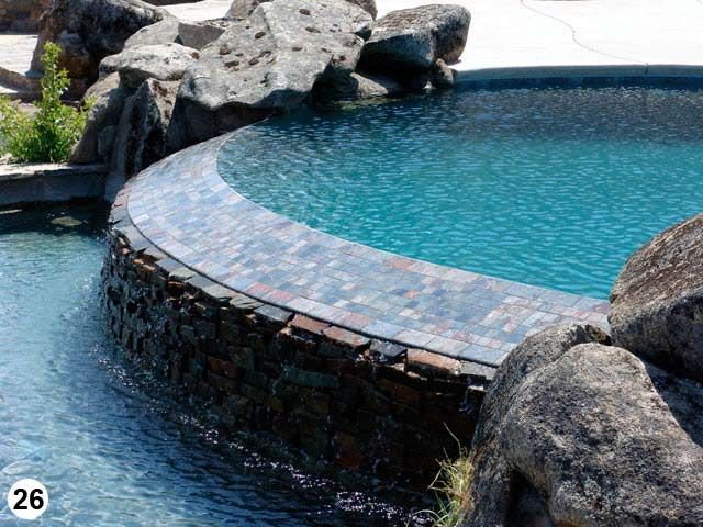 A swimming pool with a stone border and rocks around it