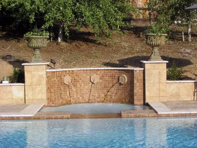 A swimming pool with a fountain in the middle of it