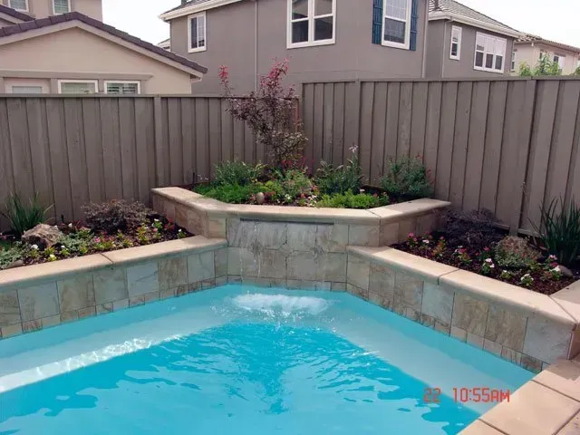 A swimming pool with a fence and a house in the background