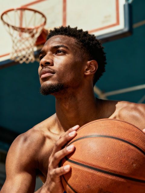 confident basketball player preparing for performance, calm expression, close-up mid-torso, textured ball, focused gaze
