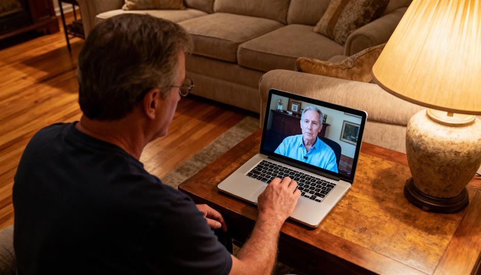 middle aged man sitting in front of his laptop in Chesapeake during a virtual hypnosis session