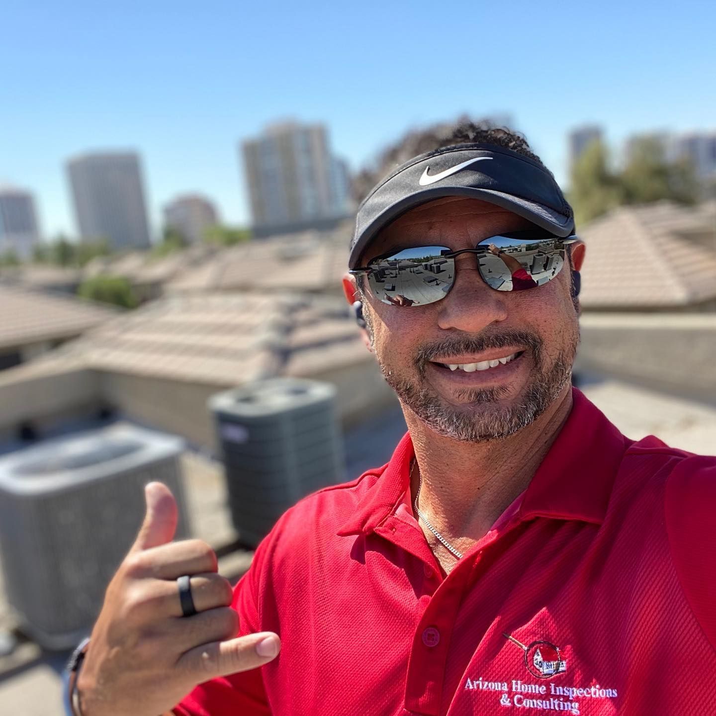 A man wearing sunglasses and a hat is giving a thumbs up