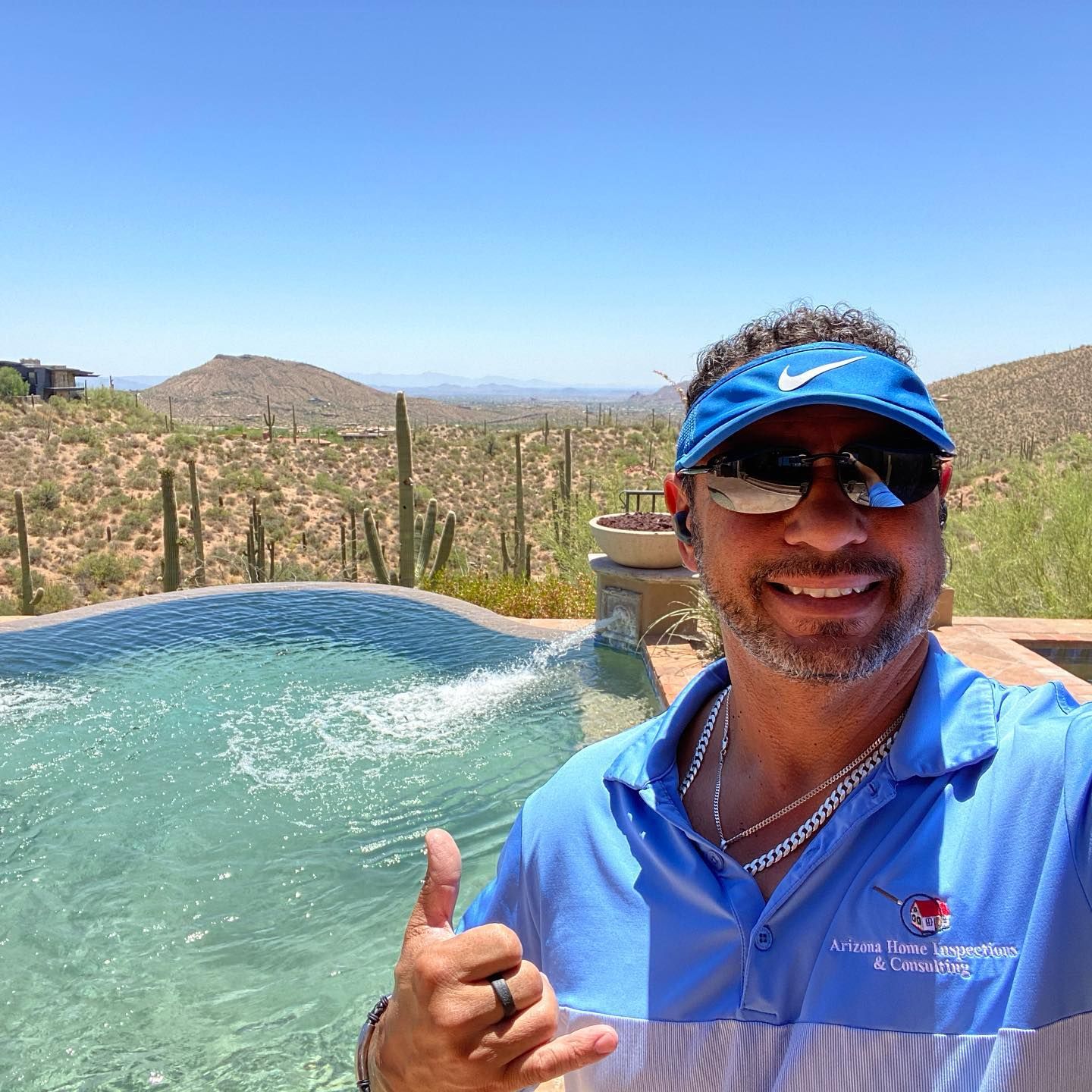 A man in a blue shirt is giving a thumbs up in front of a pool