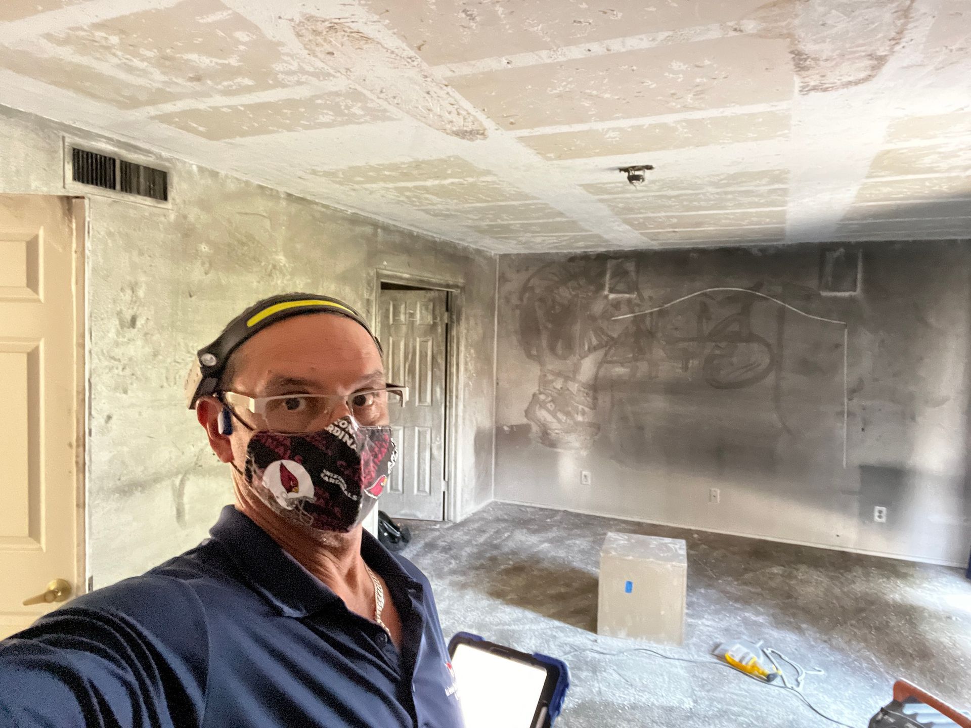 A man wearing a mask and goggles is taking a selfie in a room.