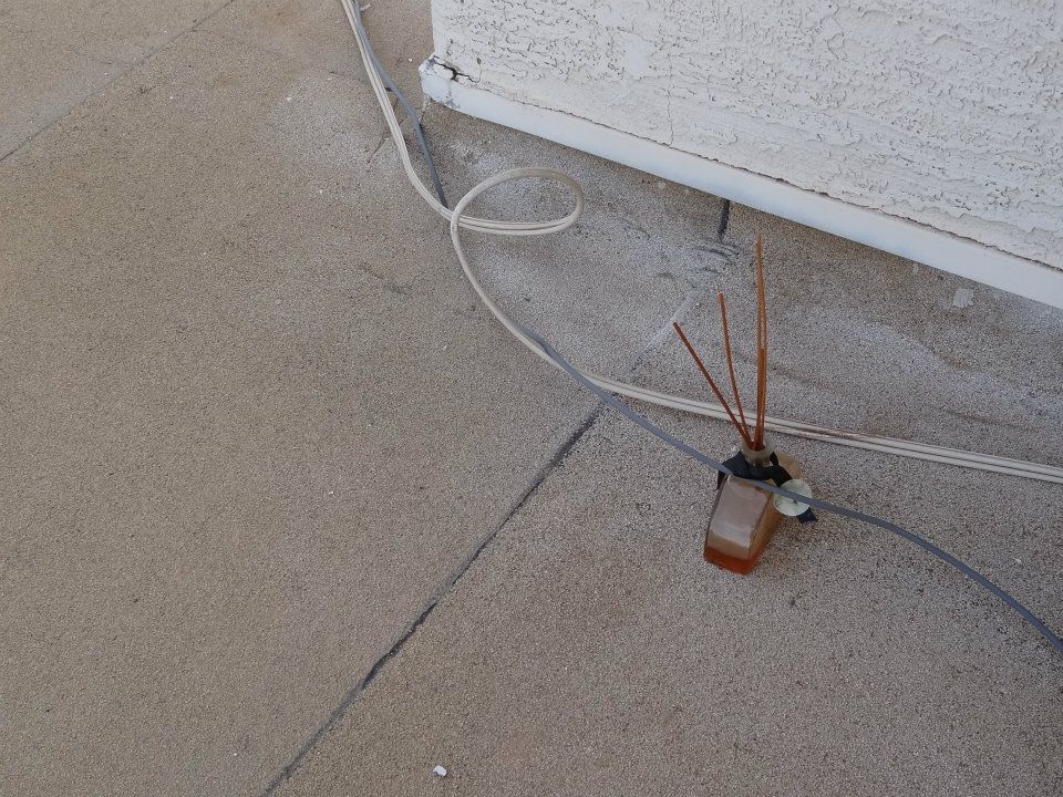 A bottle of reed diffuser is sitting on the ground next to a wire