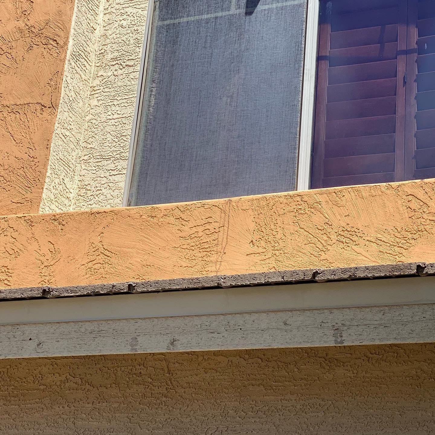 A close up of a building with a window and shutters