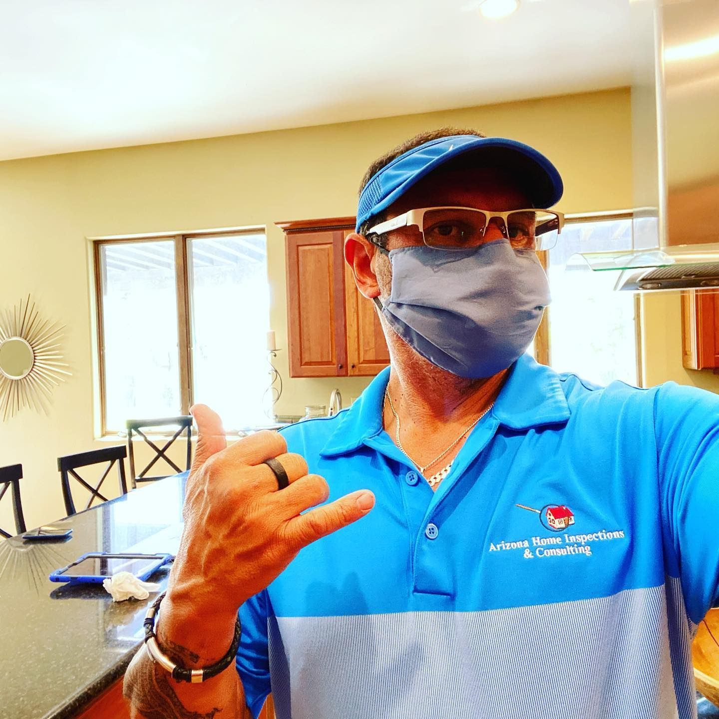 A man wearing a face mask and sunglasses is giving a thumbs up