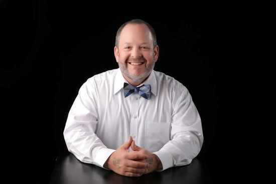 Denny Humphrey sitting with back blackground professional headshot