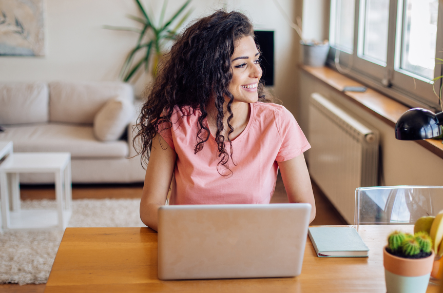 A woman is sitting at a table using a laptop computer.
