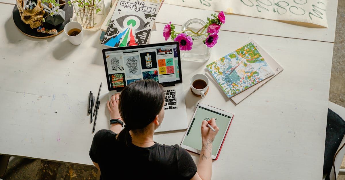 A woman is sitting at a table with a laptop and a tablet.